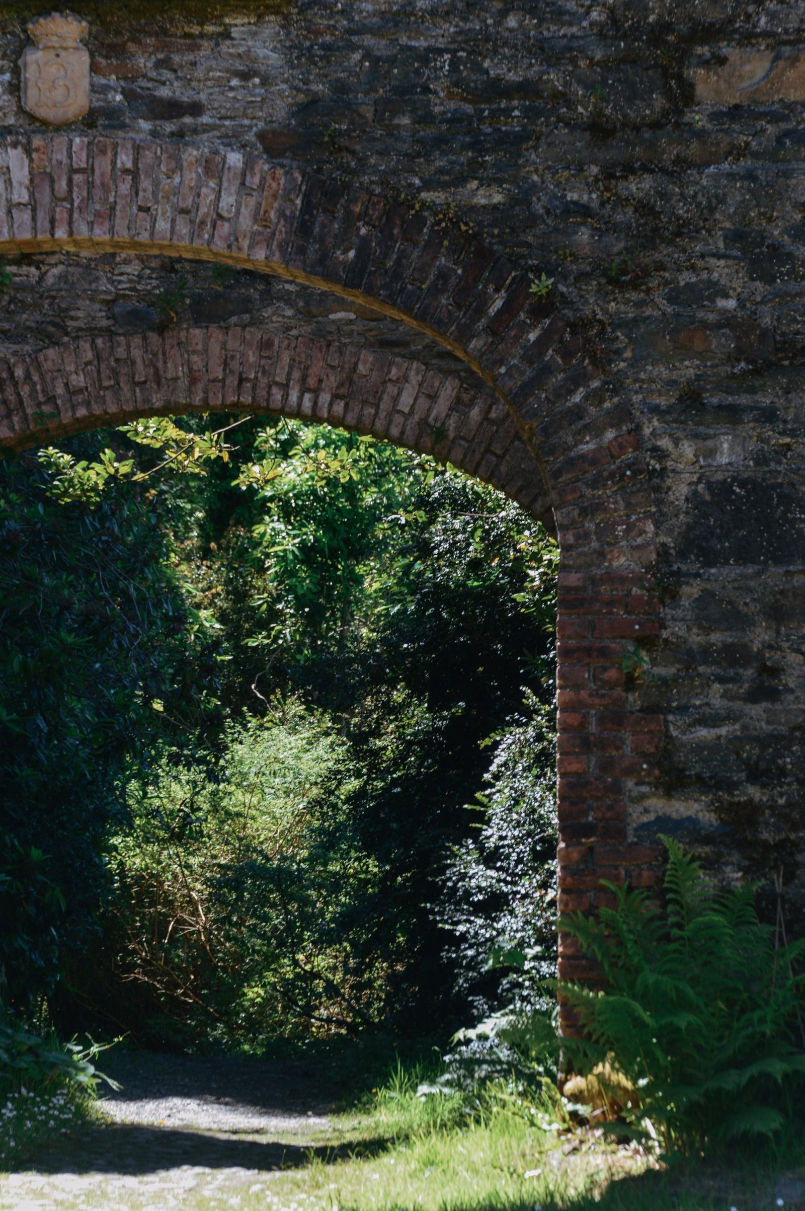 Beautiful stone archway leading to a lush garden in Bantry, Ireland.